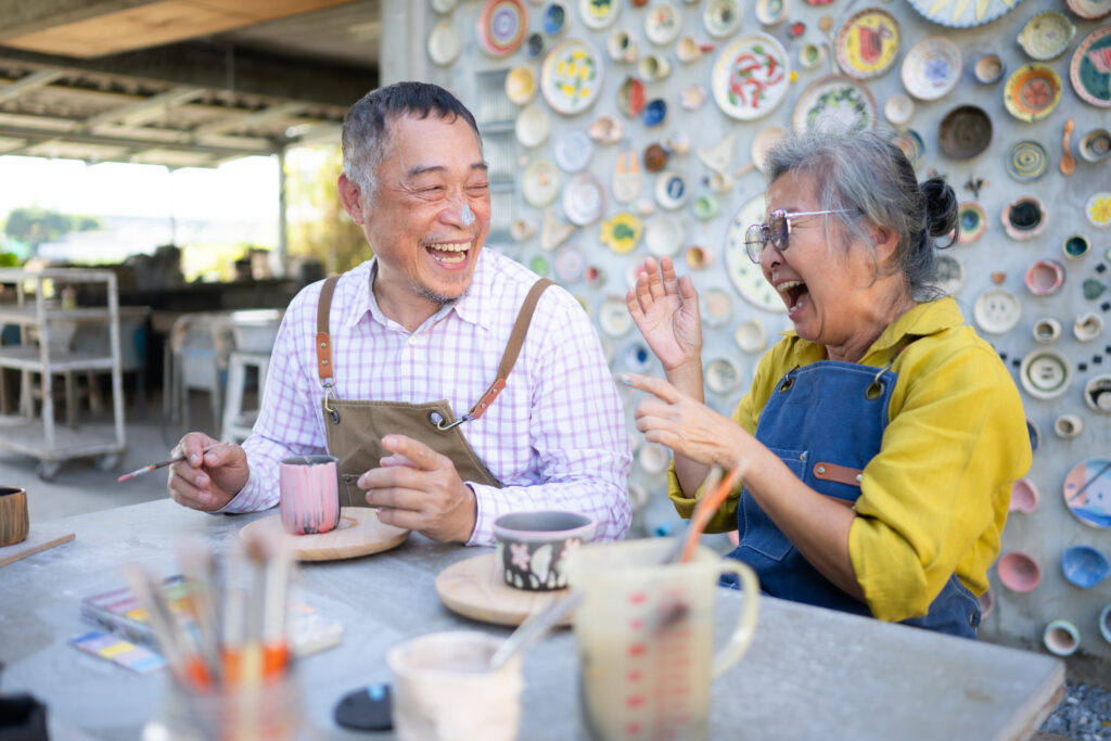 In the pottery workshop, an Asian retired couple is engaged in pottery making and clay painting activities.
