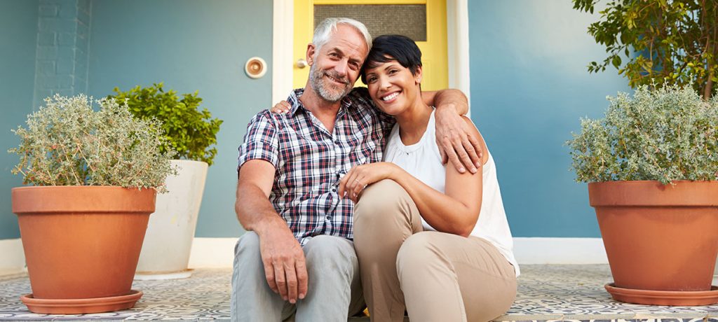 mature couple sitting on the steps of their front porch