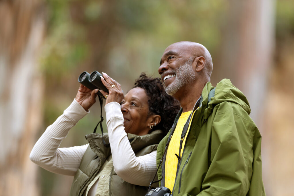 senior man and woman outside with binoculars to watch birds